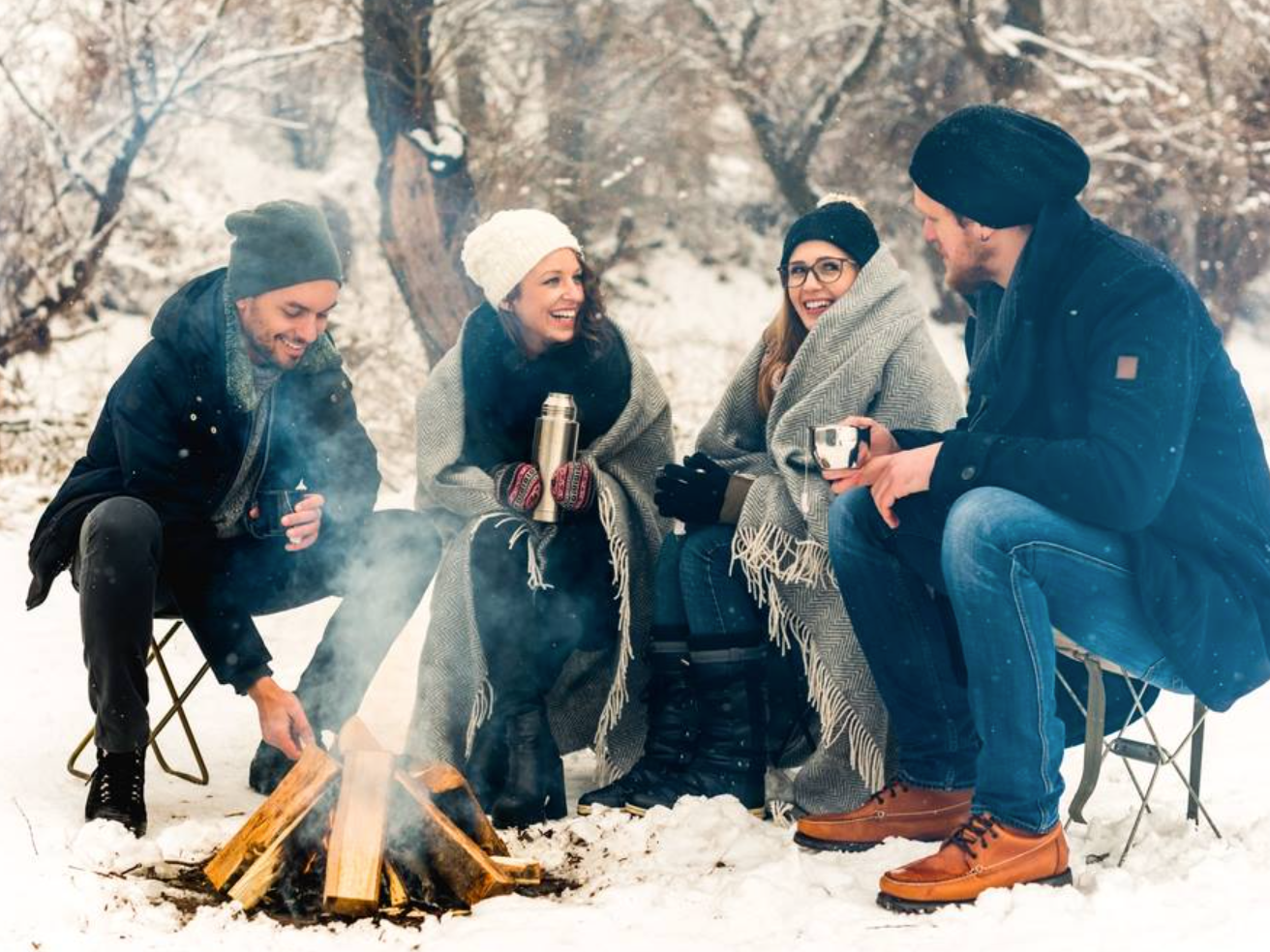 four friends sat by campfire on winter road trip with cruise canada on rv rental