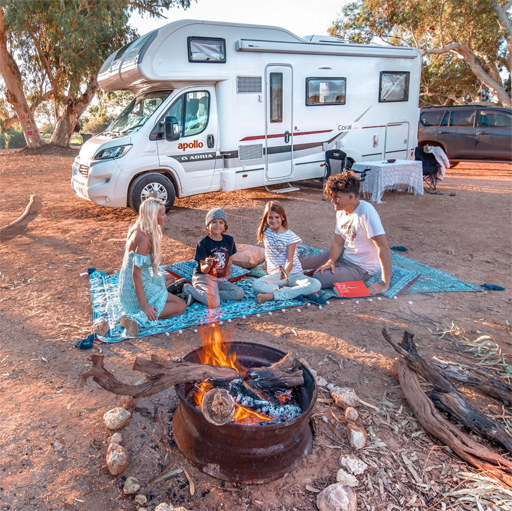 Family outside an Apollo motorhome by an open fire