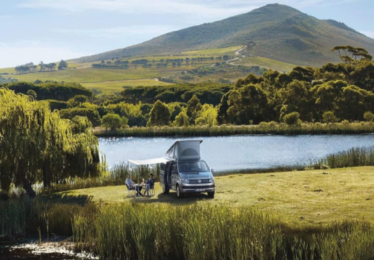 people sat outside motorhome hire with green scenery